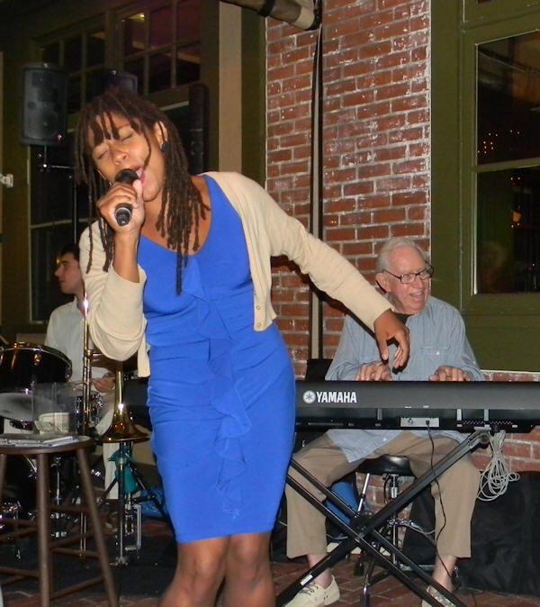 young African-American woman with dreadlocks in a blue dress singing her heart out