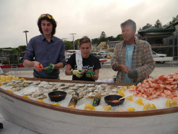 3 people shucking oysters on a boat filled with ice