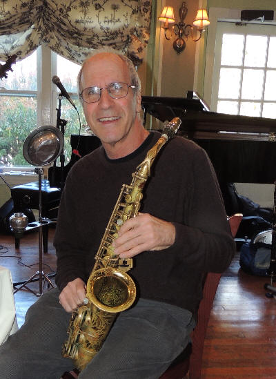 Billy sitting in chair, smiling, lovingly holding his alto sax